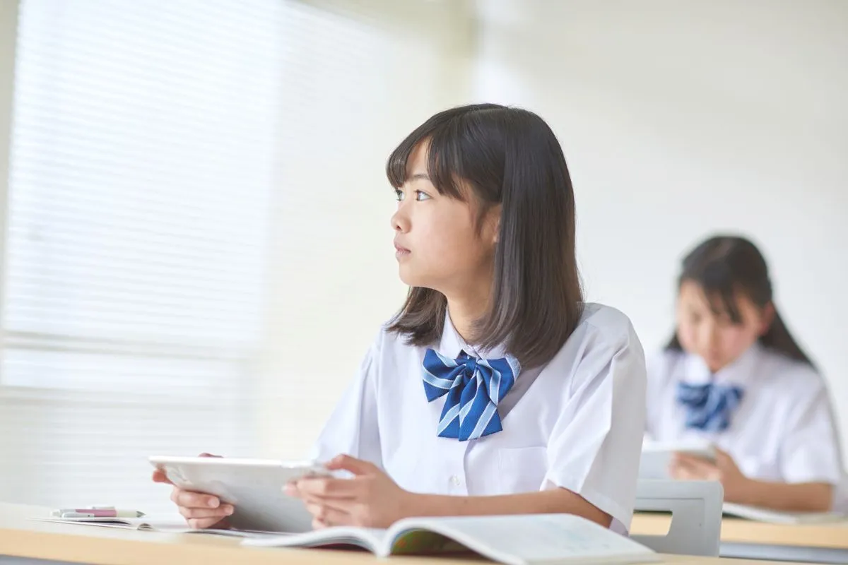 女子高生がタブレットを持って学習している画像